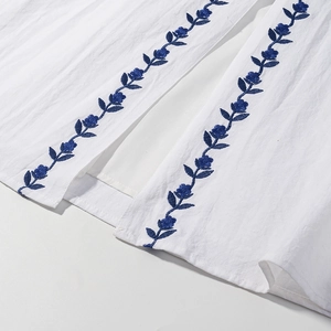 Detailed view of blue floral embroidery on white cotton linen vacation dress bodice