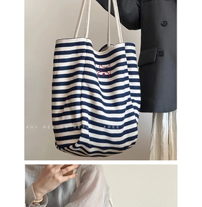 Detail of blue and white striped canvas tote with animal embroidery and rope handles