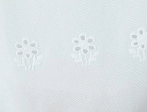 Gros plan sur un tissu en dentelle blanche avec broderie florale et détails ajourés
