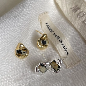 Close-up of gold and silver irregular waterdrop earrings with black-white spotted textures