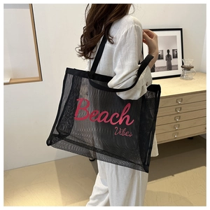 Detail of black mesh beach bag with pink Beach Vibes print shown on model's shoulder