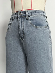 Detailweergave van high waist jeans met klassieke metalen knoop en riemlussen ontwerp