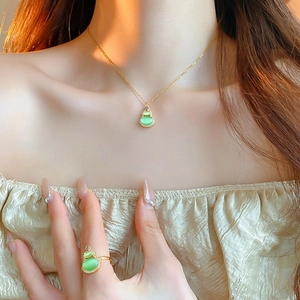 Detailed close-up of a gold-plated hulu necklace and ring set with green cat eye stones