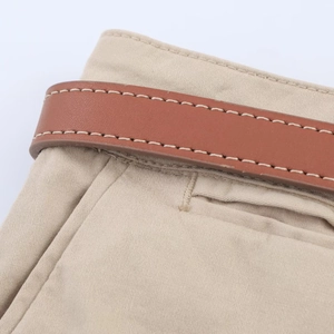 Detailed close-up of beige twill cotton shorts with high-density stitching and brown belt