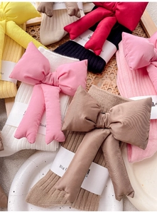 Flat lay of colorful knitted mid-calf socks with large 3D cotton-filled bows for women