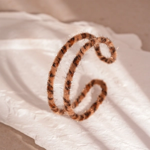 Close-up of leopard print faux fur bracelet with gold glitter and soft velvet texture