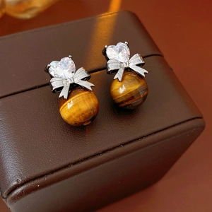 Macro shot of tiger eye stone earrings with zircon heart and silver bow detail