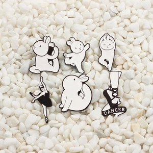 Close-up of 6pcs black and white enamel dancer bunny pins on white pebbles background