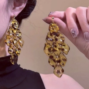 Close-up of leopard print acrylic petal fringe earrings with amber resin texture