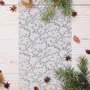 Detail of grey star pattern mesh table runner with Christmas pine and ornaments decor