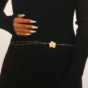 Detail van de boheemse frangipani bloem tailleketting op een zwarte jurk