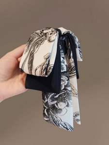 Détail d'une pince à cheveux à nœud fleuri noir et blanc avec rubans fluides