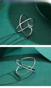 Macro shot of minimalist silver X-shaped crossover ring showing smooth geometric details