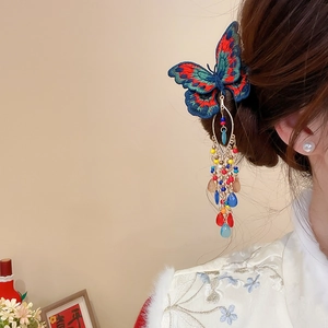 Detailed close-up of embroidered butterfly hair clip with colorful beaded tassels