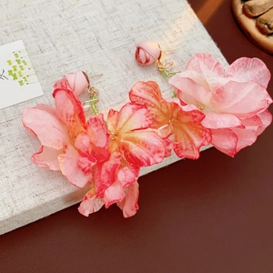 Nahaufnahme der floralen Ohrringe mit pink-orangefarbenem Farbverlauf und Perlendetails