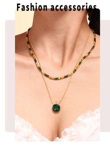 Dettaglio di una collana a due strati dorata con pendente in cristallo verde e perline
