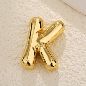 Macro shot of 3D balloon style letter K pendant with polished gold finish on stone
