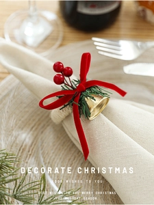 Close-up of Christmas napkin ring with red velvet bow, pine needles and gold bells
