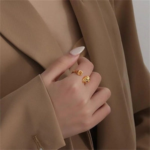 Close-up of a gold skull and hand open ring worn by a model in a punk style
