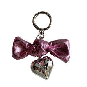 Pink metal bow keychain with silver heart pendant and engraved bow pattern on white background