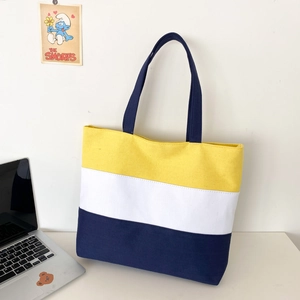 Detailed view of large canvas tote bag featuring yellow, white, and blue color-blocking