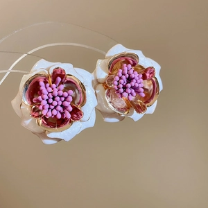 Vue détaillée de boucles d'oreilles fleurs 3D avec bords dorés et centre violet