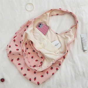 Détail de l'imprimé fraise sur le sac cabas en velours côtelé rose avec accessoires