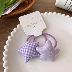 Detail of two purple star-shaped fabric hair ties with plaid and polka dot patterns