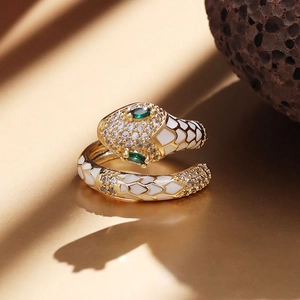 Macro shot of gold-plated snake ring with white enamel, green stone eyes and micro-inlays