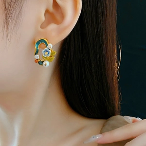 Detail of vintage flower earrings with green enamel and pearls worn by a model