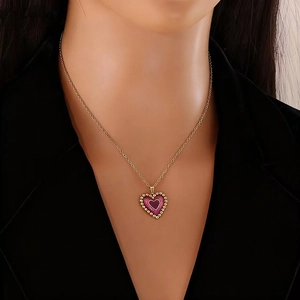 Close-up of golden necklace with layered purple heart pendant worn by a female model