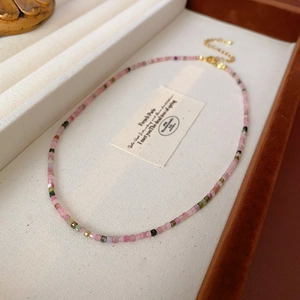 Détail du collier de perles colorées avec fermoir doré dans une boîte à bijoux beige