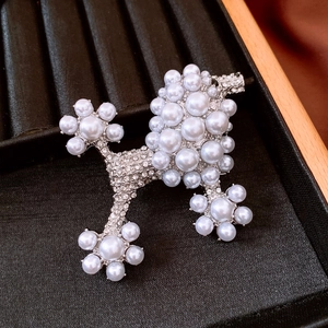 Close-up of luxury poodle brooch featuring sparkling rhinestones and white pearls inlay
