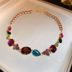 Detail of necklace with multi-colored gemstones and champagne pearls in gold settings