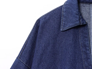 Dettaglio del colletto e della cucitura della spalla di una camicia in denim blu scuro