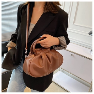Detail view of brown pleated cloud bag featuring soft leather texture and long shoulder strap