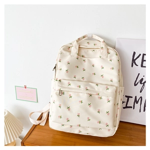 Detail of floral cream backpack with pink flower patterns on a wooden desk