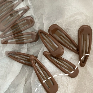 Close-up of brown teardrop-shaped BB clips scattered on white textured paper