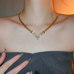 Close-up of a gold-plated V-shaped pendant necklace with sparkling diamonds on a model