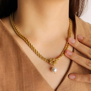 Detail of gold twisted rope chain necklace with a round white pearl pendant on clothing