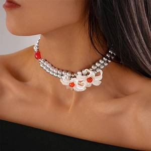 Macro view of double-layer grey faux pearl necklace with white lilies and red bead accents