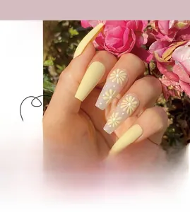 Detailed view of yellow matte press-on nails with white daisy floral patterns and solid colors