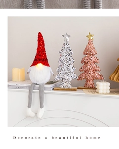 Nahaufnahme von leuchtendem Wichtel und Pailletten-Weihnachtsbäumen auf einem Tisch