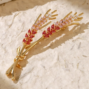 Close-up of golden wheat brooch with pink zircon stones on textured background