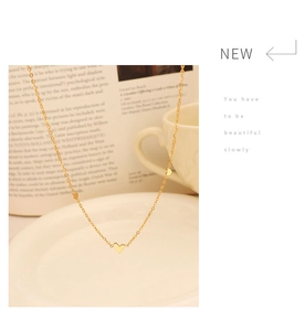 Detailed close-up of delicate 18K gold heart charms on a minimalist necklace on white plate