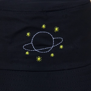 Gros plan sur le tissu en sergé de coton noir avec broderie planète et étoiles