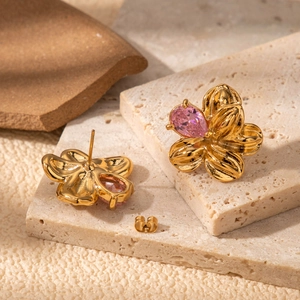 French vintage gold flower earrings with pink pear-cut crystal on stone background