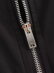 Détail macro d'une fermeture éclair en métal argenté sur une veste baseball noire