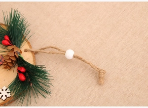 Detailed close-up of Christmas wood slice ornament with pine needles and red berries