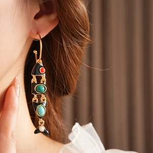 Detail of vintage enamel fish earring with red and green turquoise on female model